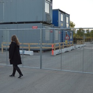 En dame går foran en letvektsgrind montert på en byggeplass