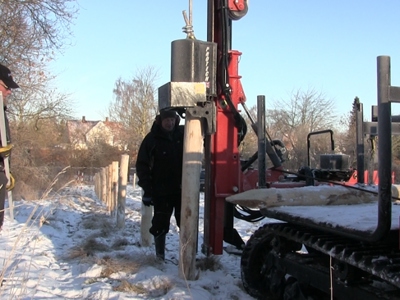 To menn monterer gjerde i snø