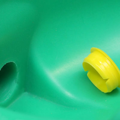 Nærbilde av en grønn drikkekopp med en gul plastpropp ved en åpning.