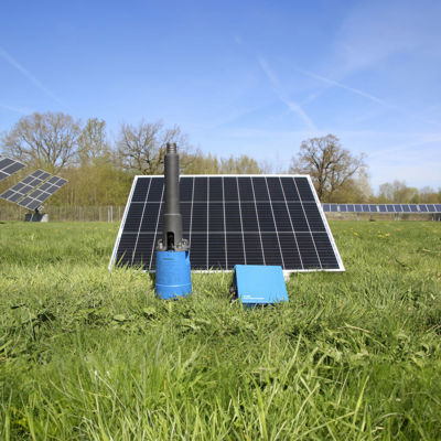 Solcelledrevet pumpe med solcellepanel og kontrollenhet på en grønn eng