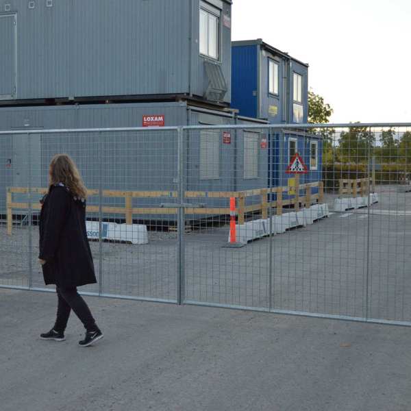 En dame går foran en letvektsgrind montert på en byggeplass
