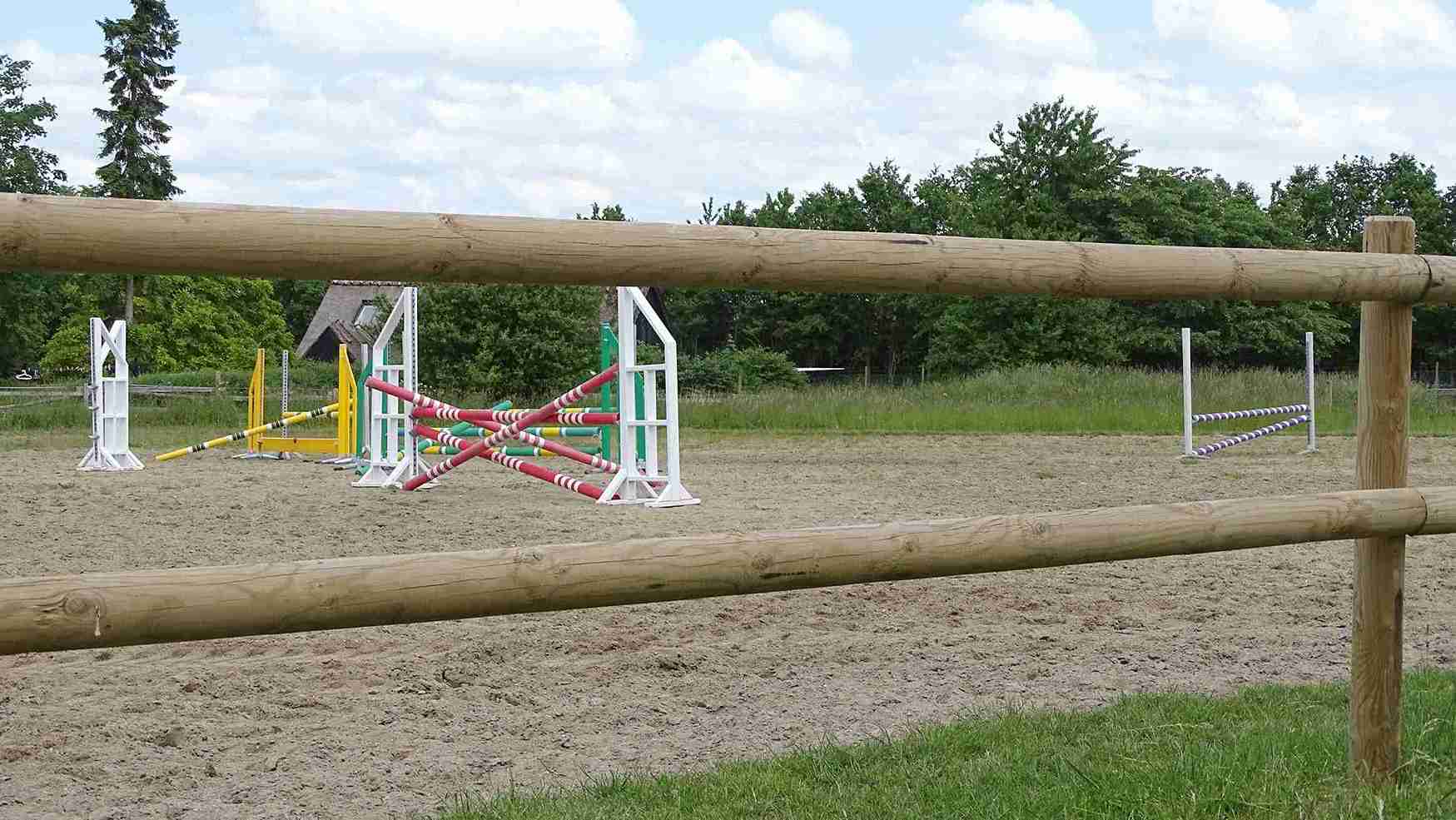 Hoppene på en ridebane kan skimtes mellom lekterne på banens tregjerde.