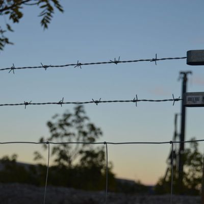 Nærbilde av piggtråd på toppen av et gjerde på en byggeplass
