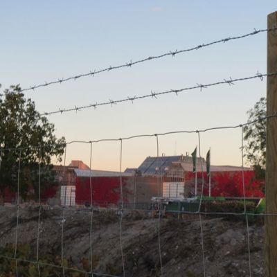 I bakgrunnen er en rød bygning, i forgrunnen er det et byggeplassgjerde