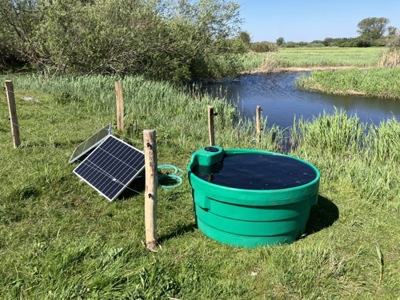 Soldrevet markpumpe som står ved en elv