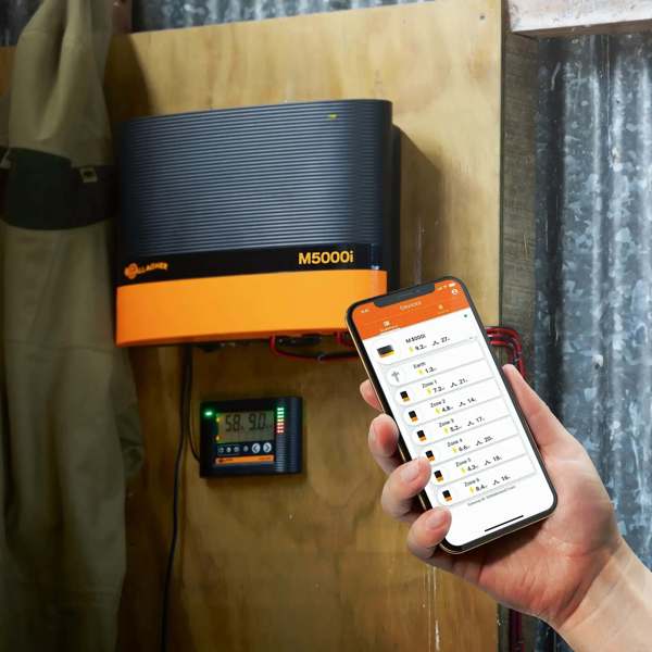 Gjerdeapparatet M5000 henger på en vegg, mens tilhørende mobilapp vises.