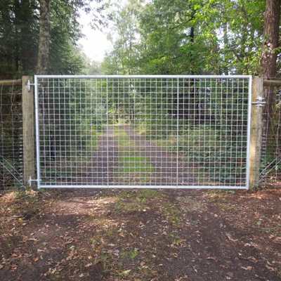 I forgrunnen er det en lettvektsgrind med gitter. Bak den er det en sti i en skog