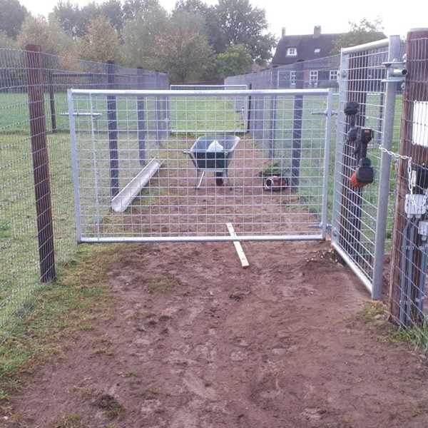 En trillebår står bak en lettvektsgrind med netting.
