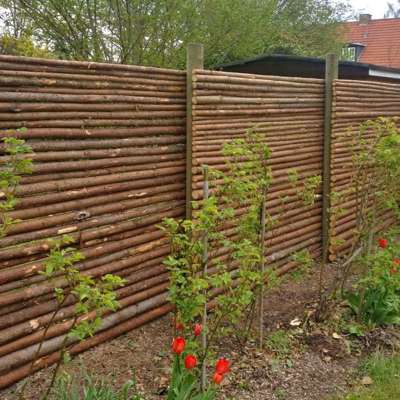 Noen vakre planter er plantet mot et stokkegjerde med bark