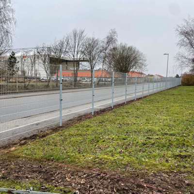 En bedrift har satt opp et grått panelgjerde ut mot en vei for å beskytte dem mot tyveri og hærverk